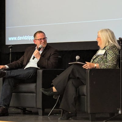 David Zipper and Jennifer Dill seated in chairs on a stage
